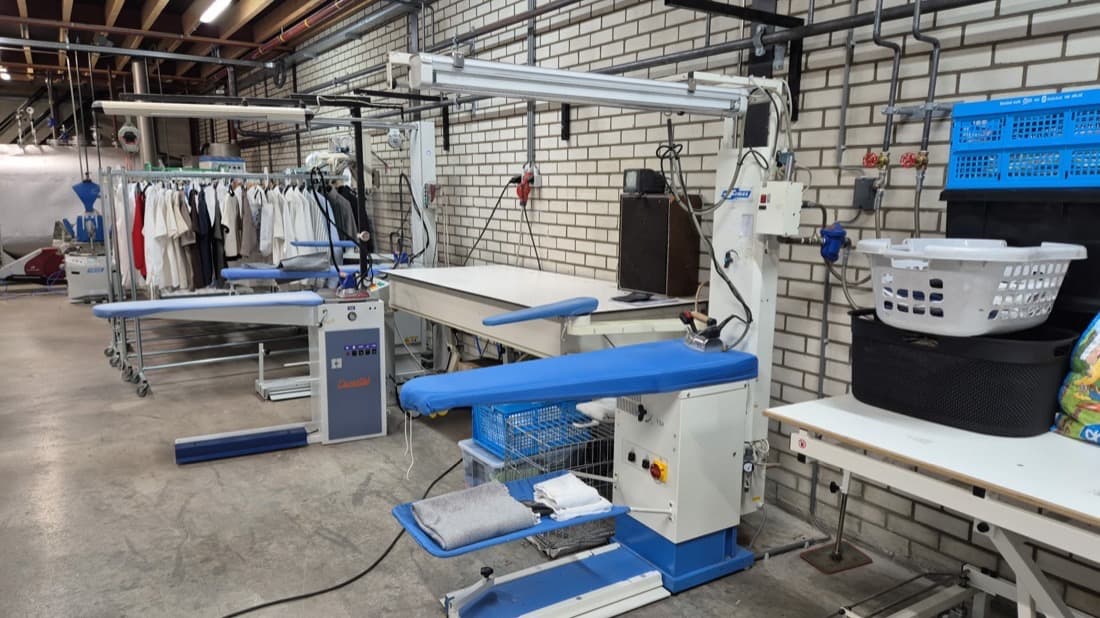 De werkruimte met perstafels en strijkstations bij Wasserij Lividus