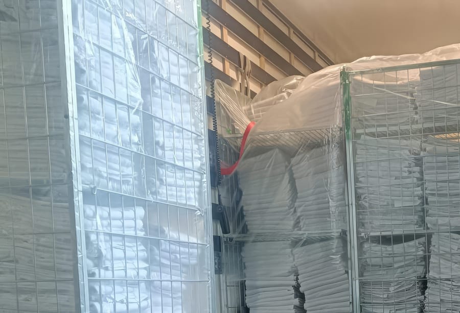 Rolcontainers vol ingepakt linnengoed, klaar voor transport